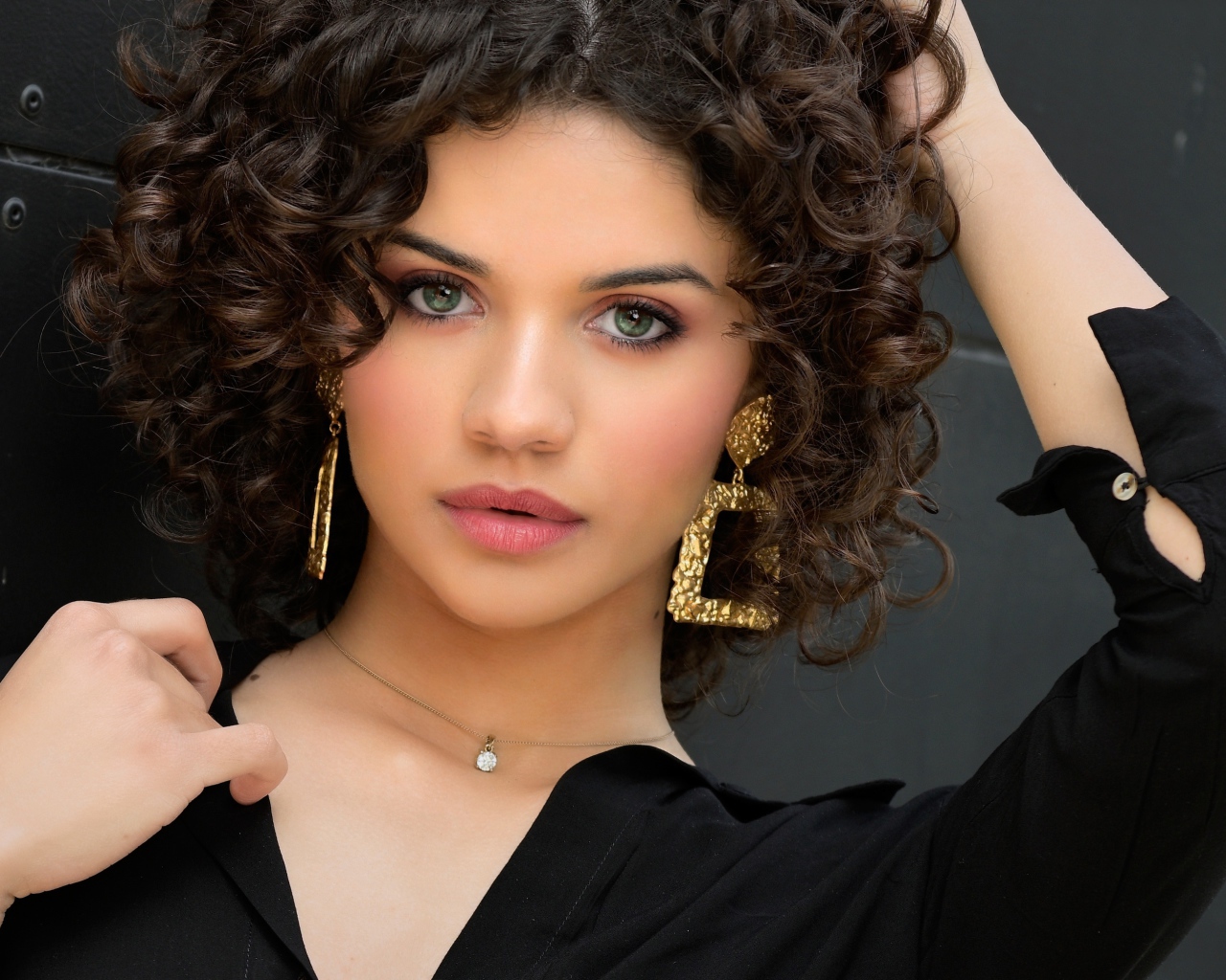 Кудрявая девушка с рукой в волосах в черной рубашке 