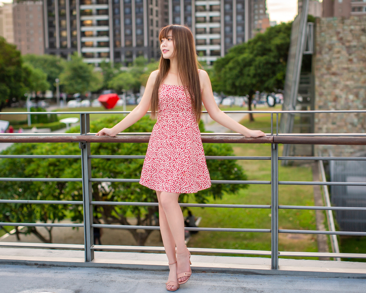 Милая девушка азиатка в платье стоит у перил 