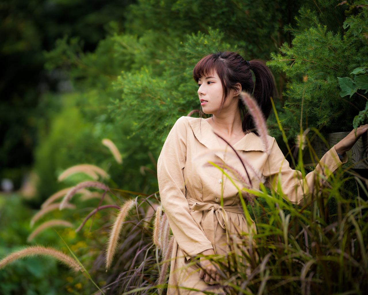 Милая азиатка в пальто в парке 