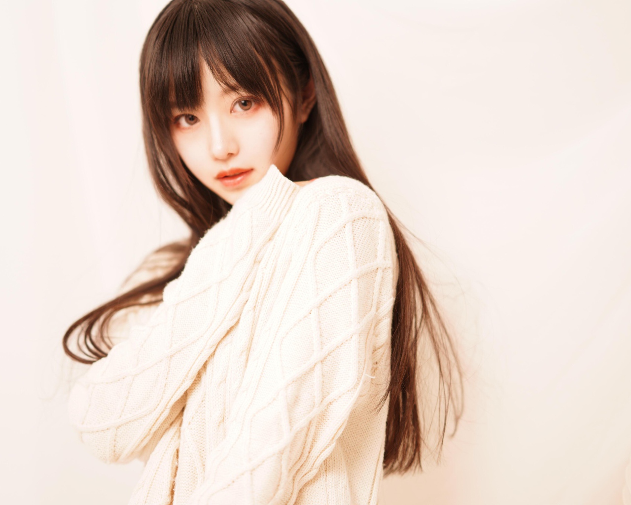 Милая азиатка в белом свитере на розовом фоне