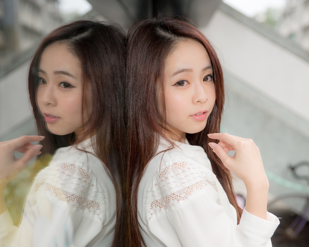 Милая азиатка в белой рубашке отражается в зеркальной поверхности 