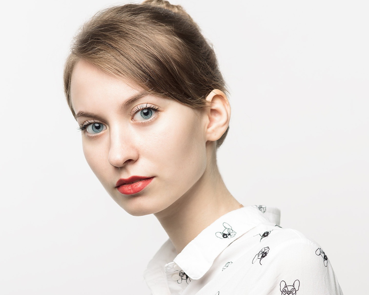 Милая голубоглазая девушка в рубашке на сером фоне