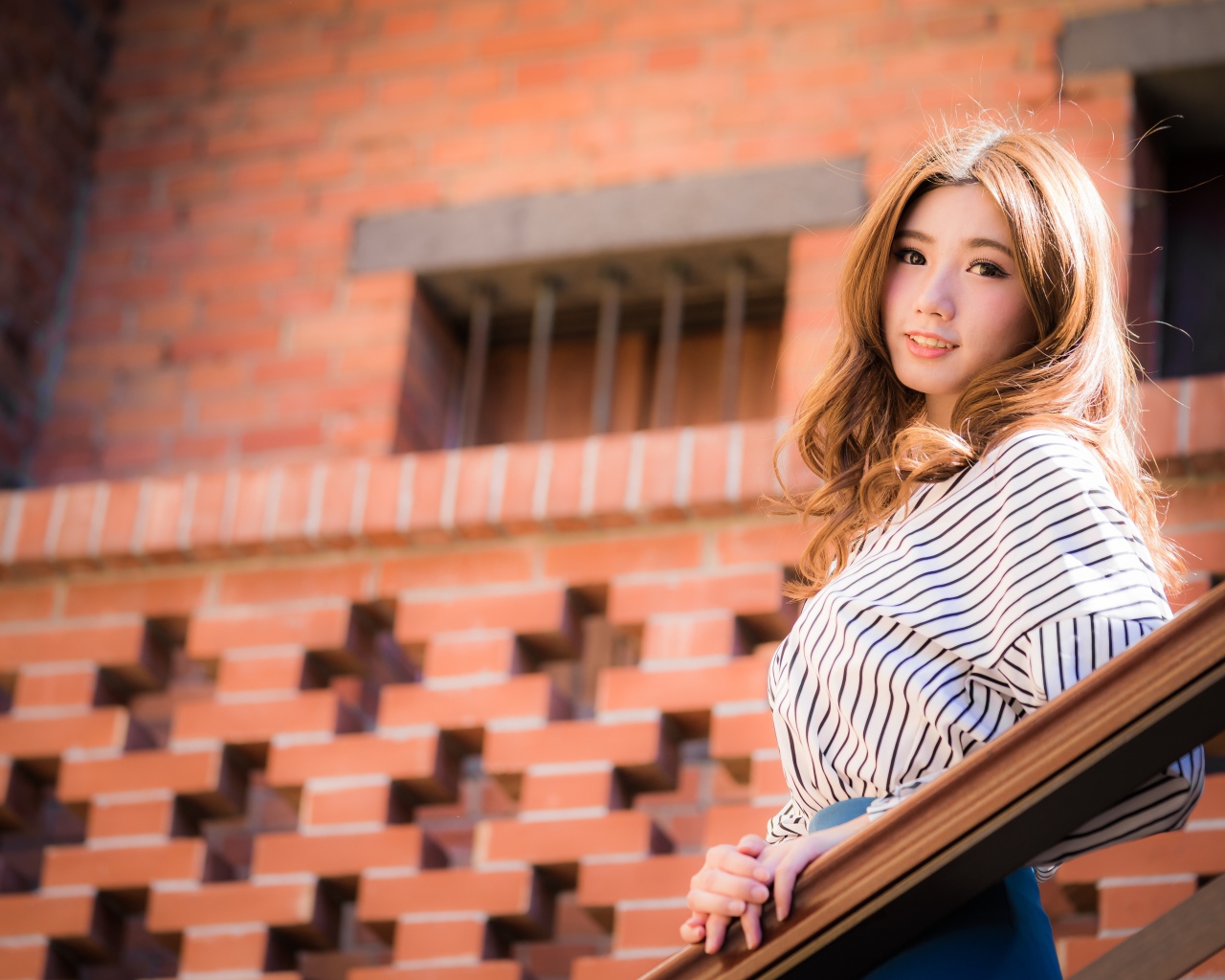 Милая девушка в полосатой рубашке стоит на ступеньках 