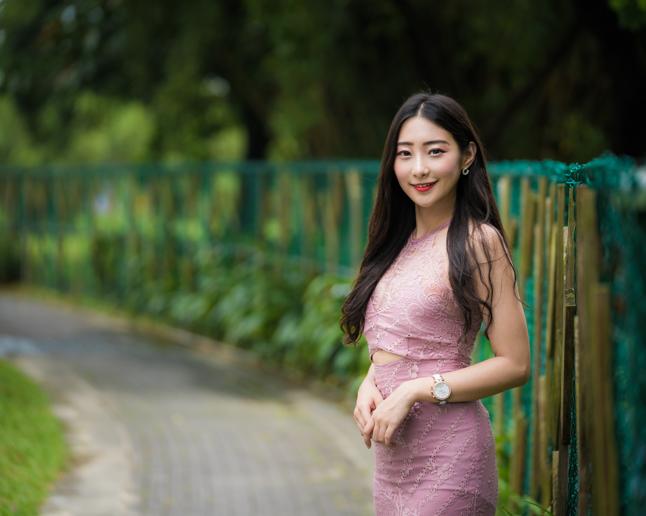 Милая улыбающаяся азиатка в костюме у забора