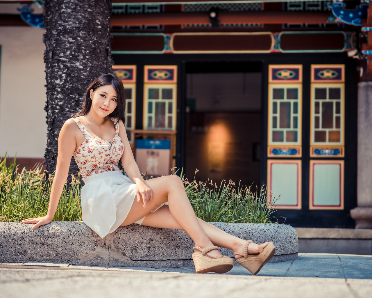 Милая улыбающаяся девушка сидит на бордюре