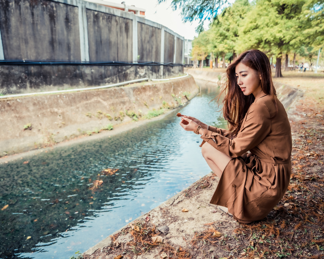 Мечтательная девушка азиатка сидит у воды