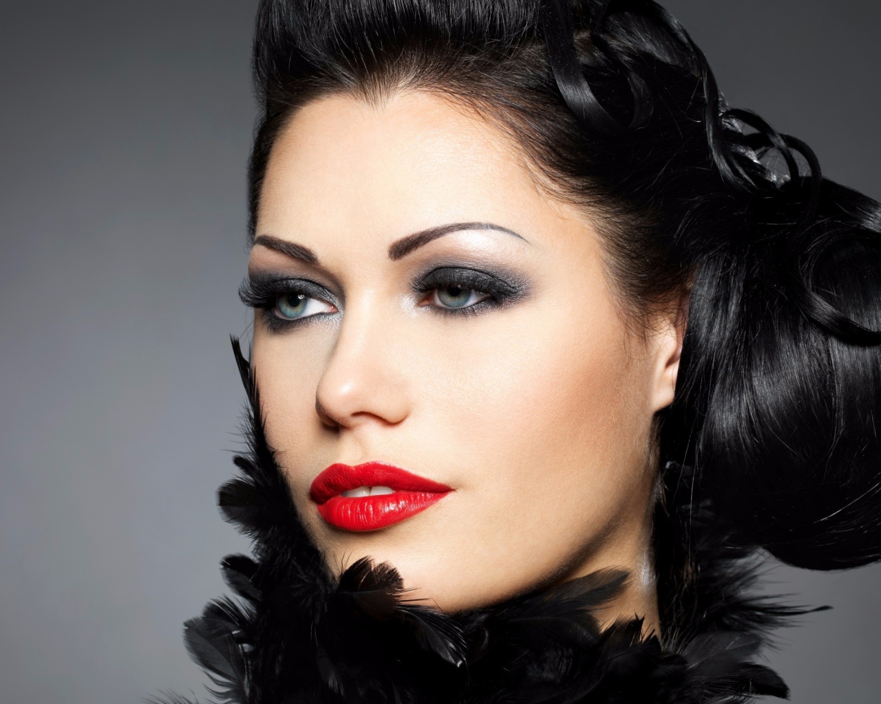 Лицо брюнетки с красивой прической на голове на сером фоне