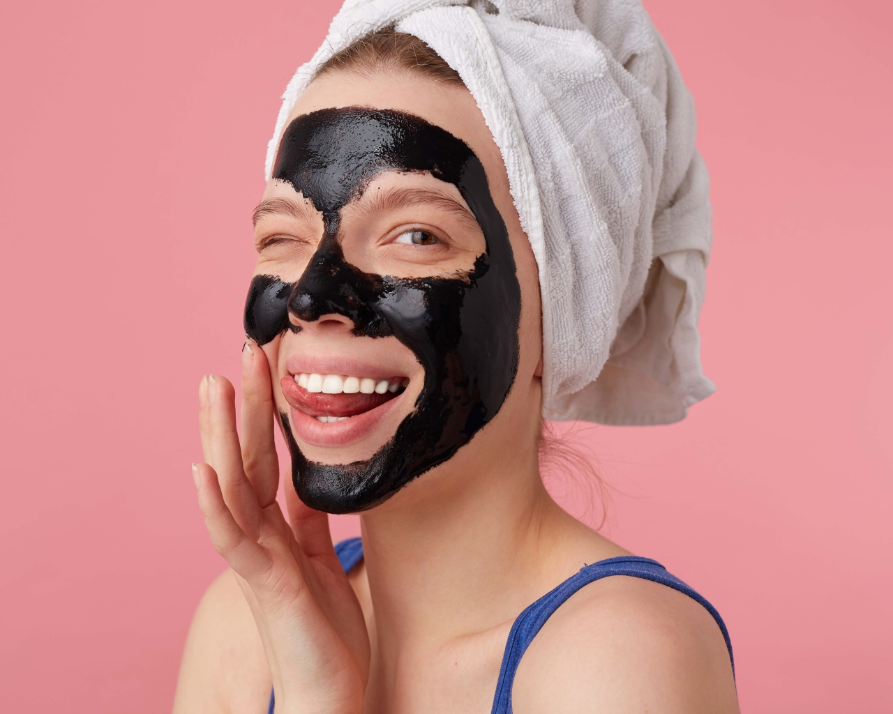 Смешная молодая девушка с черной косметической маской на лице 