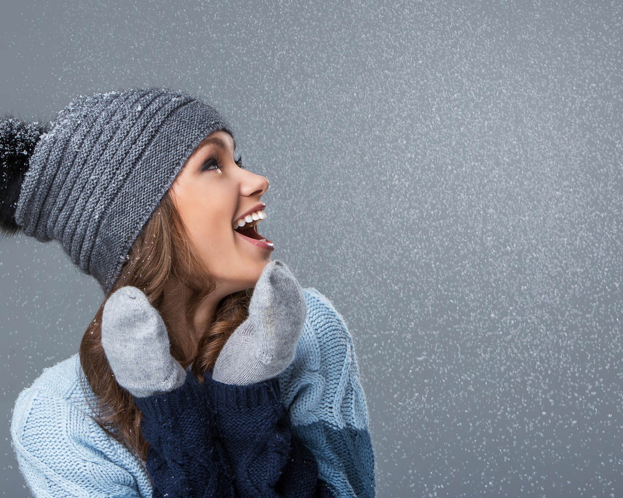 Девушка в теплой шапке на сером фоне