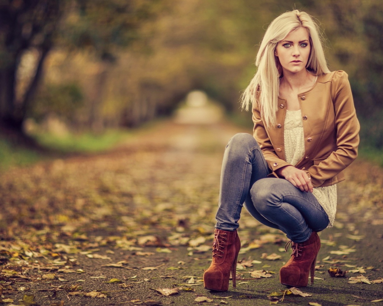 Девушка на высоких каблуках сидит на корточках в парке