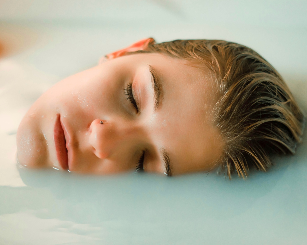 Девушка лежит с закрытыми глазами в ванной