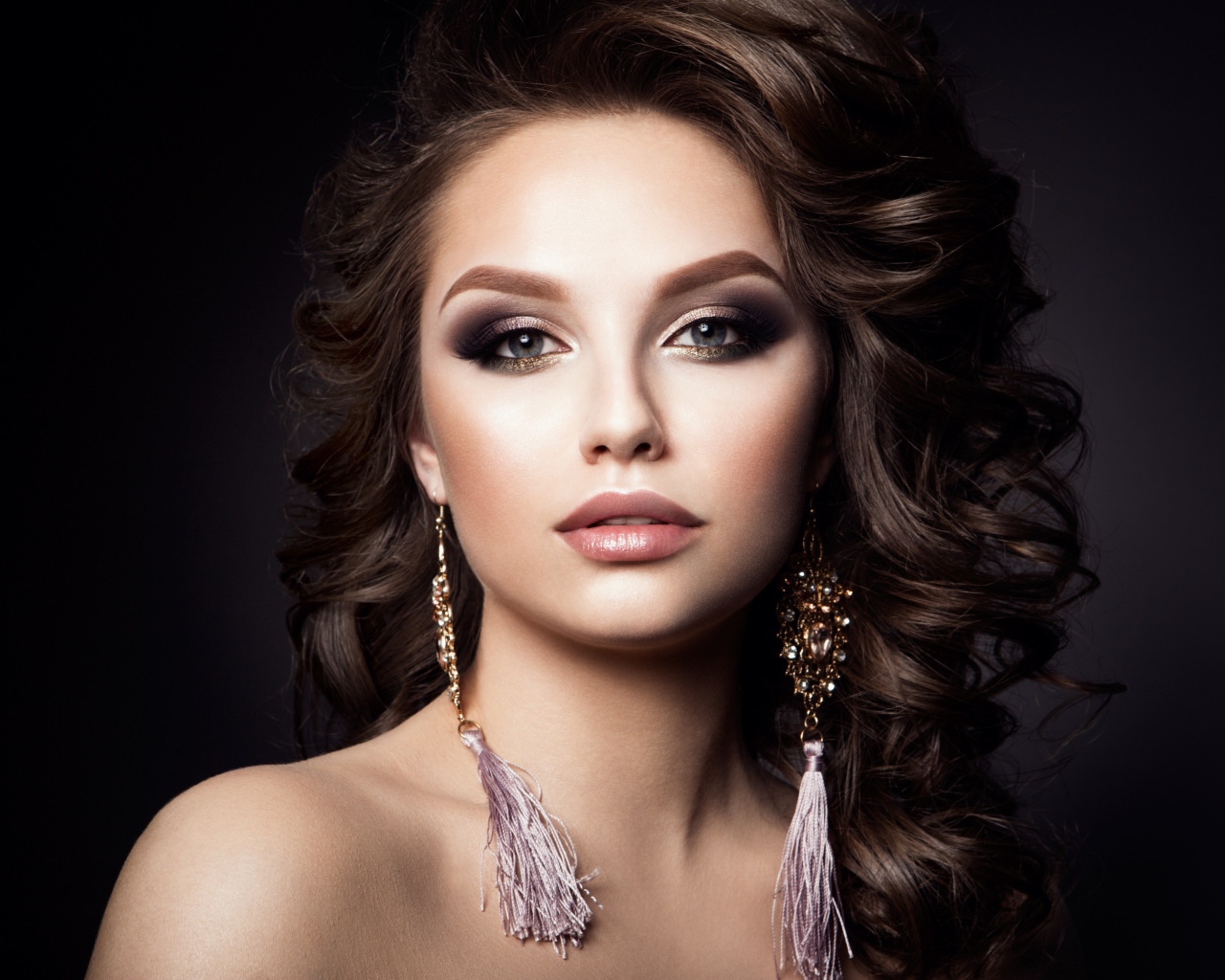 Девушка с прической с красивыми сережками на сером фоне 