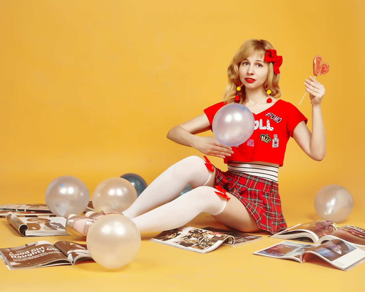 Девушка с шариками и журналами сидит на полу
