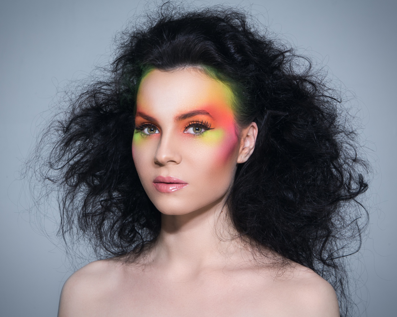 Девушка с начесом на волосах с ярким макияжем на сером фоне