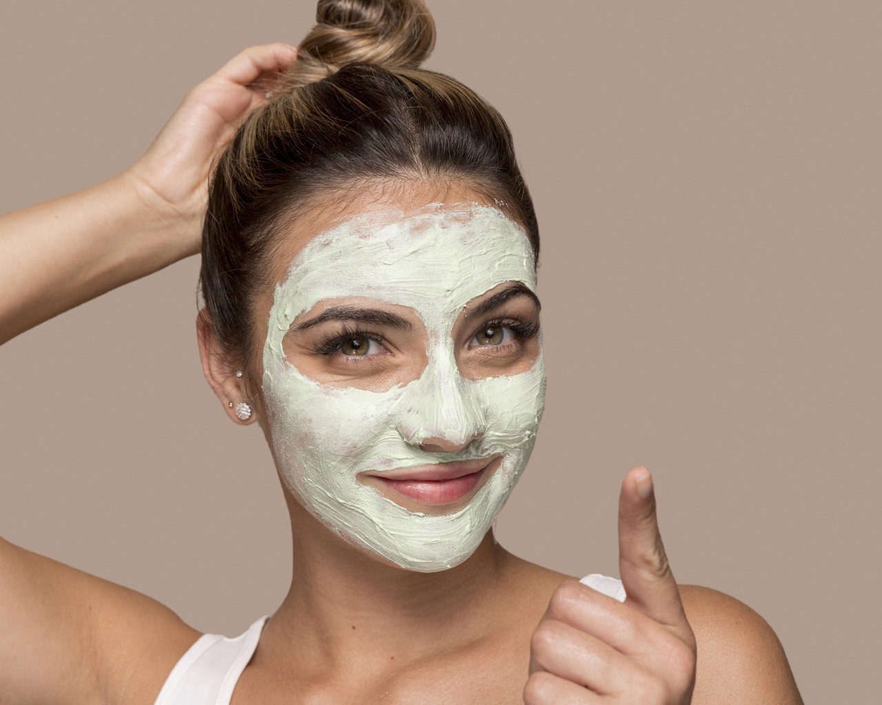 Девушка с завязанными волосами с косметической маской на лице