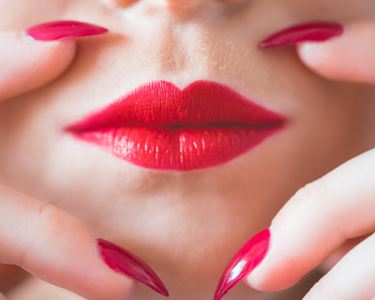 Руки с длинными красными ногтями у губ