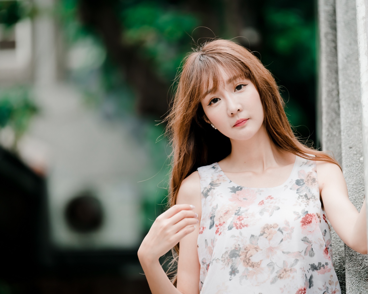 Длинноволосая азиатка стоит у стены 