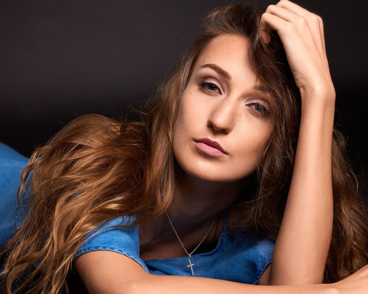 Длинноволосая шатенка лежит на полу в голубом платье 