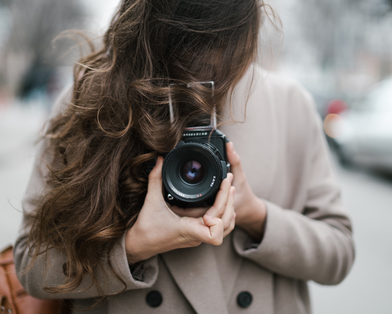 Длинноволосая девушка с фотоаппаратом в руках 