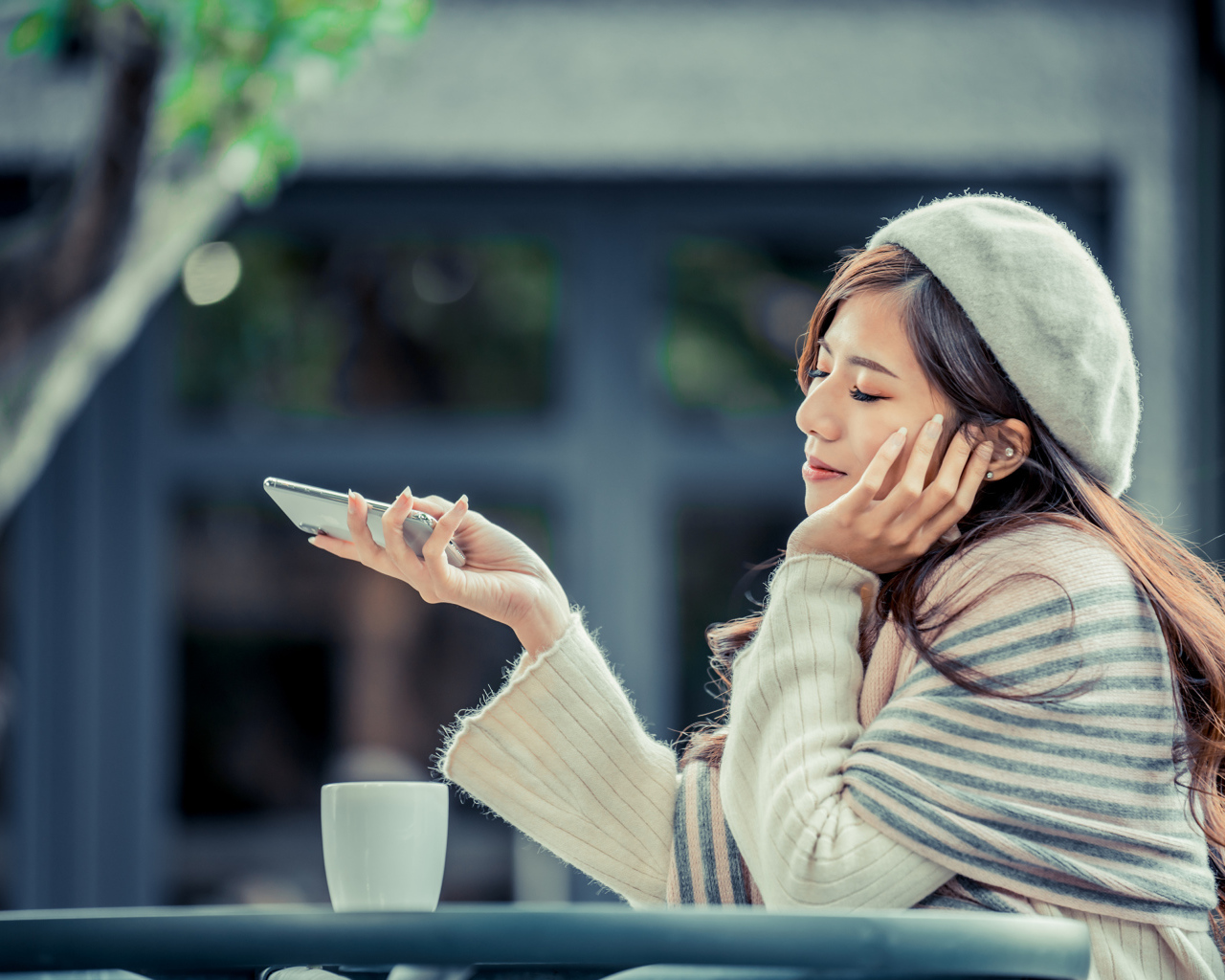 Мечтательная девушка с телефоном сидит в кафе 