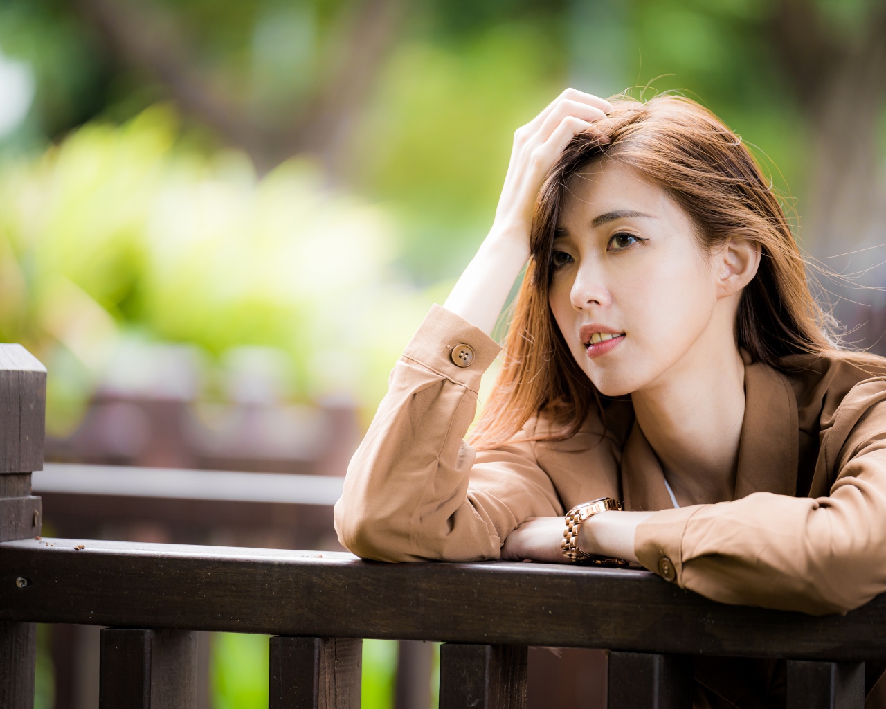 Грустная девушка азиатка стоит у деревянных перил 