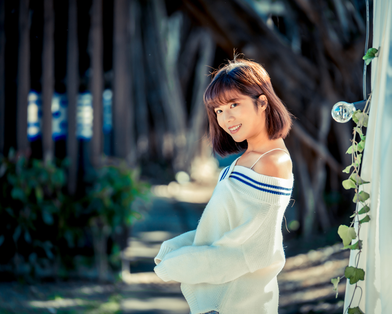 Улыбающаяся девушка азиатка в белом свитере 