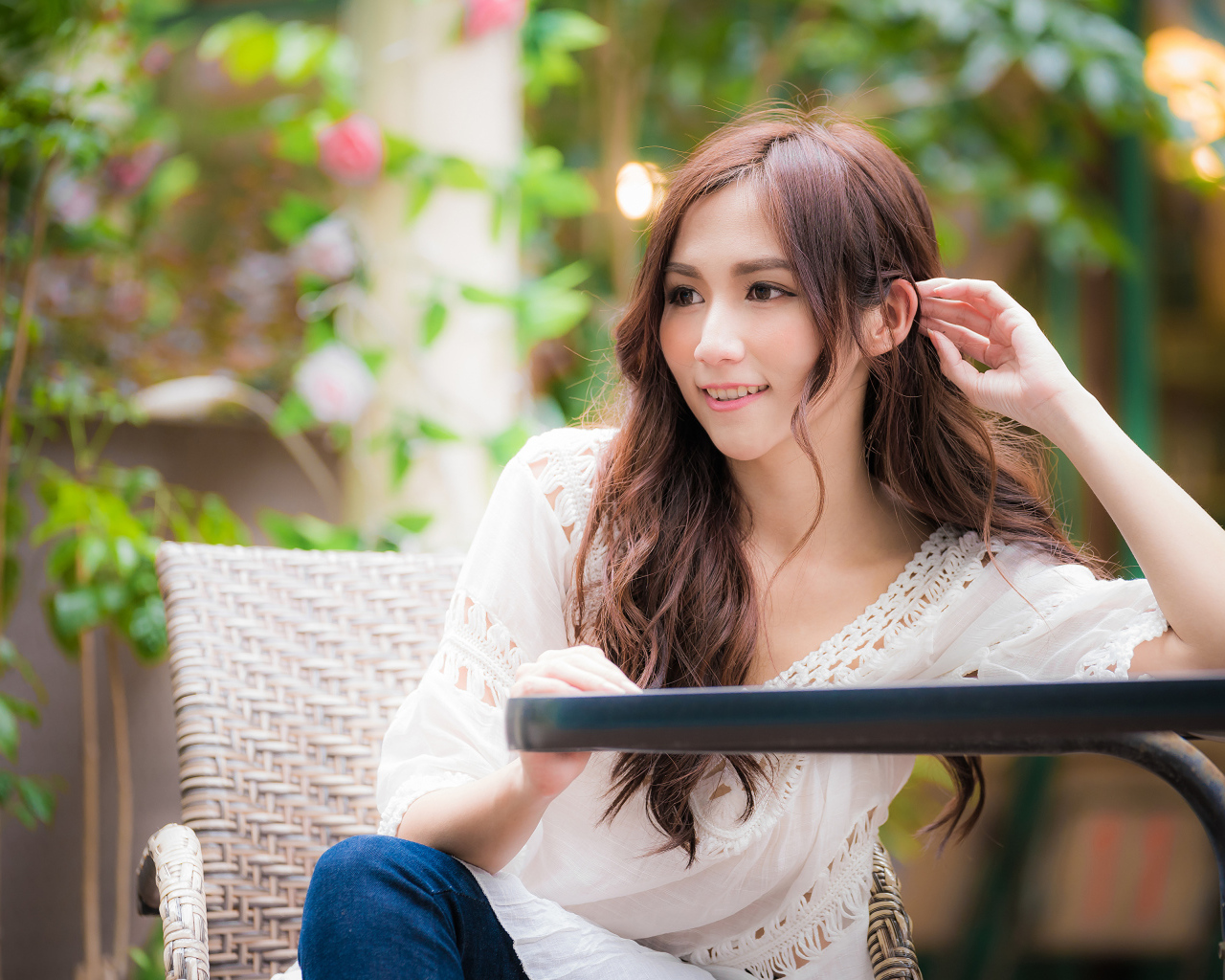 Улыбающаяся девушка азиатка сидит за столом в кафе