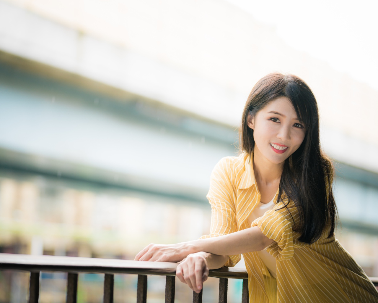 Улыбающаяся азиатка в желтой полосатой рубашке