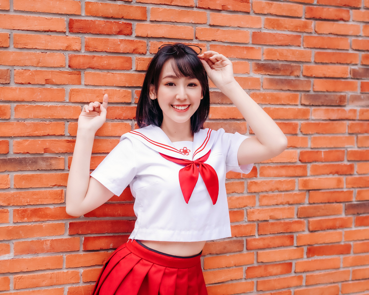 Улыбающаяся азиатка стоит у стены 