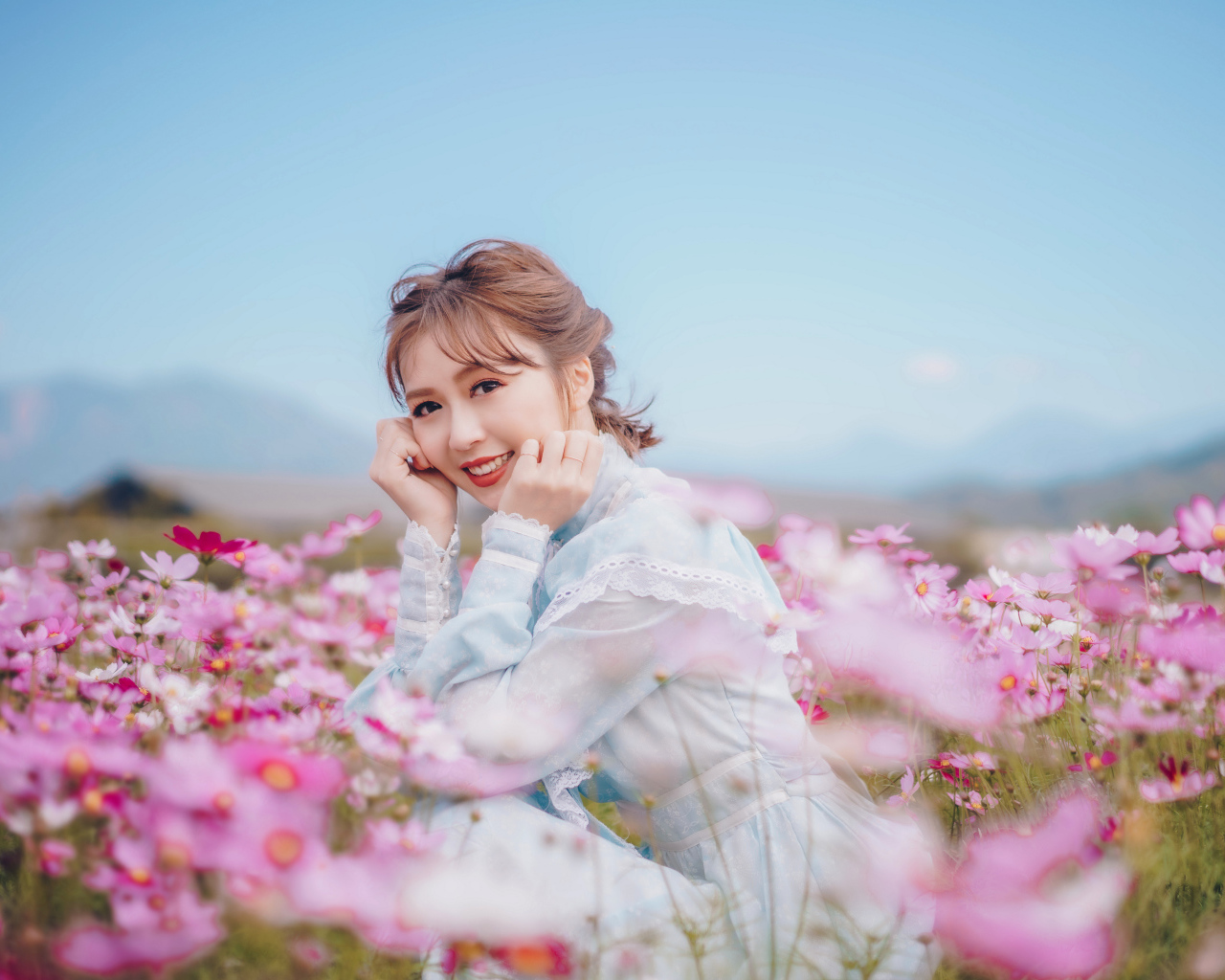 Улыбающаяся девушка азиатка на поле с цветами космеи 