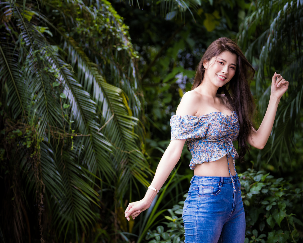 Улыбающаяся азиатка на фоне зеленых листьев