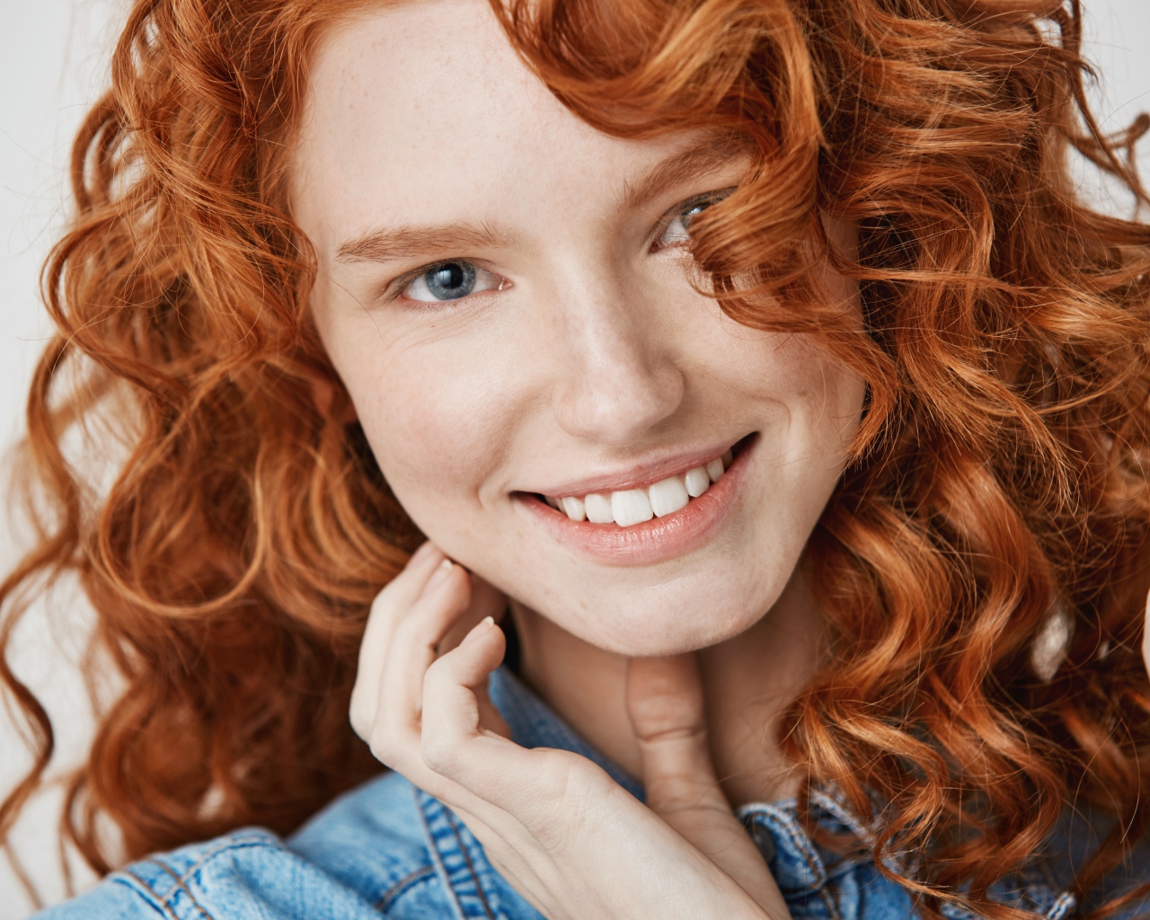 Улыбающаяся голубоглазая рыжеволосая девушка в джинсовой куртке 