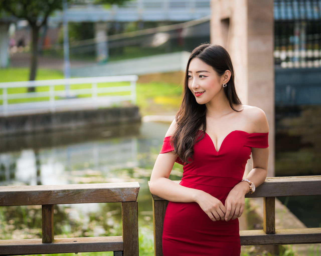 Улыбающаяся девушка в красном платье у перил 