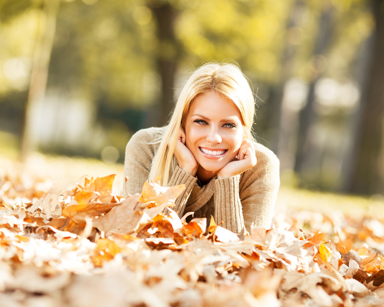 Улыбающаяся девушка лежит на сухой опавшей листве