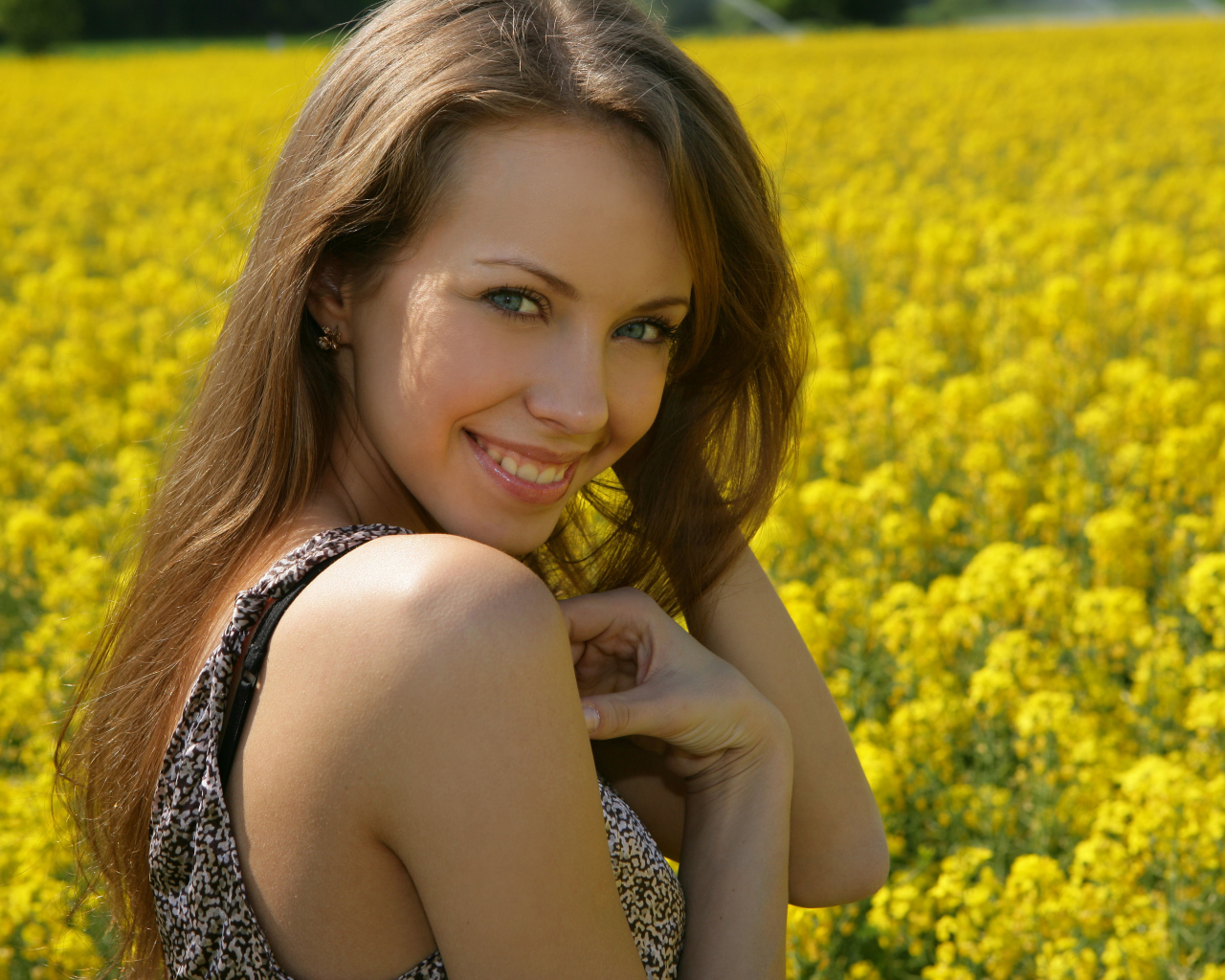 Улыбающаяся девушка на фоне поля с желтыми цветами