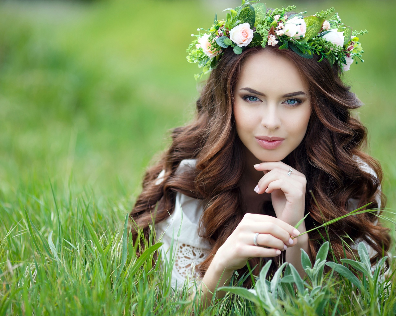 Эффектная настоящая девушка с венком на голове лежит на траве