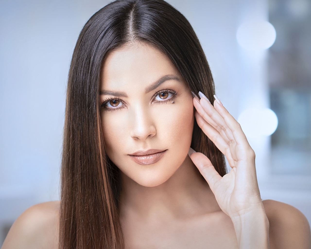 Стильная кареглазая длинноволосая брюнетка с рукой у лица