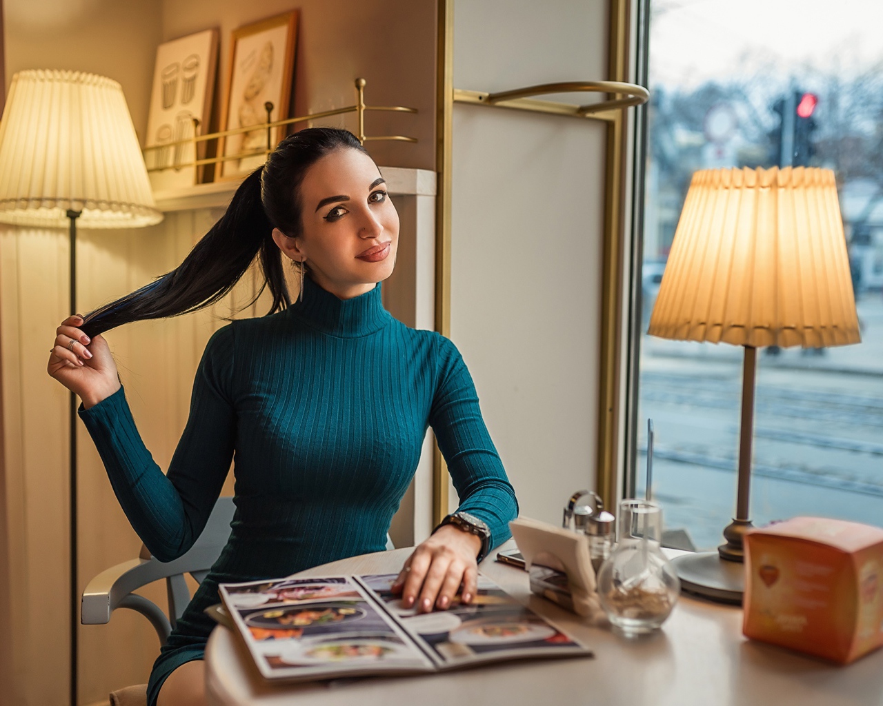 Стильная девушка в платье сидит в кафе у окна