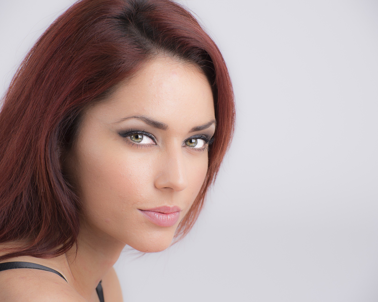 Лицо стильной девушки с зелеными глазами на сером фоне