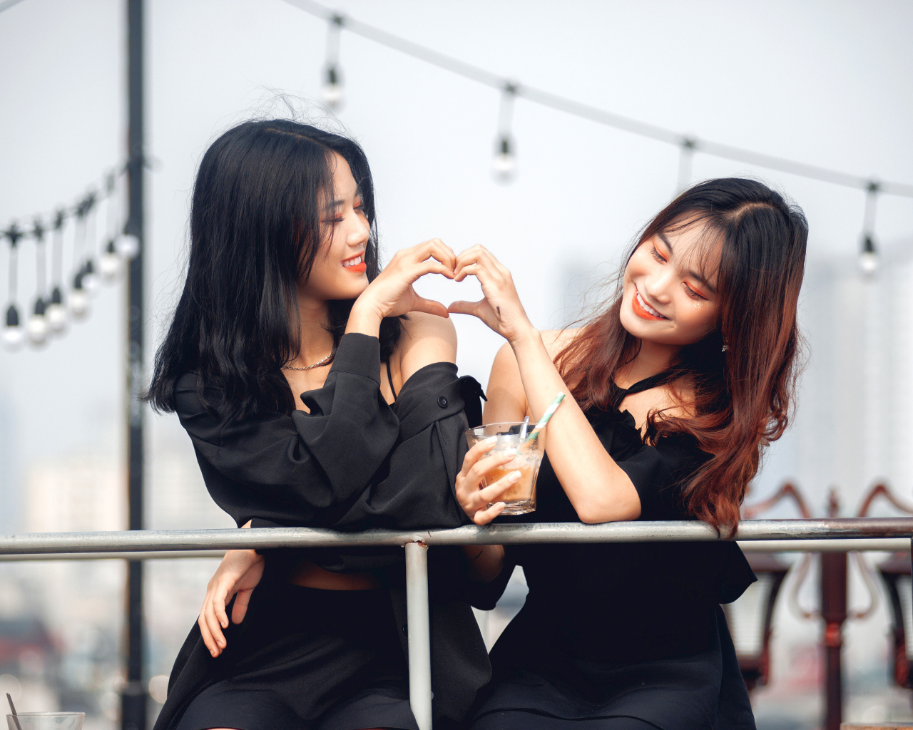 Две девушки азиатки делают сердце руками 