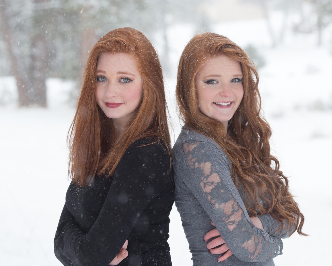 Две улыбающиеся рыжеволосые сестры на улице зимой 
