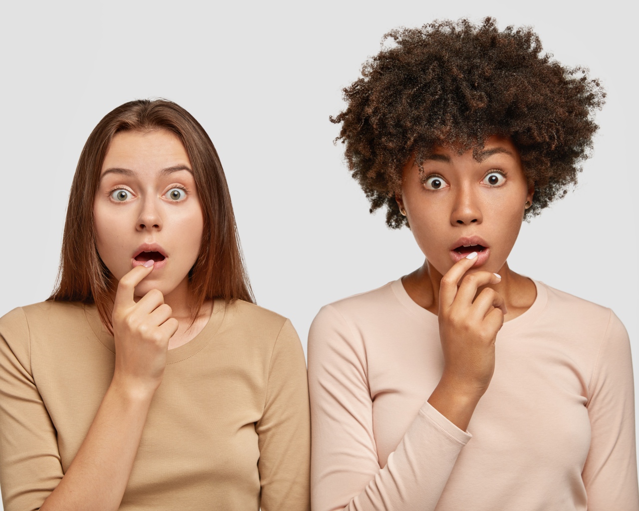 Две удивленные девушки на сером фоне 