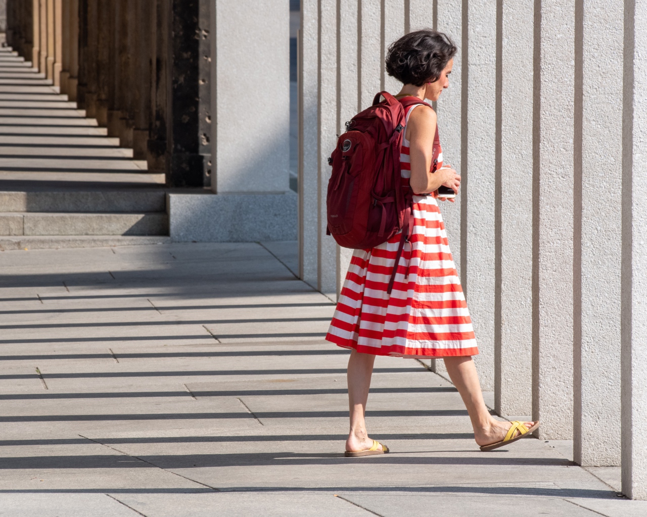 Женщина в красном полосатом платье с рюкзаком