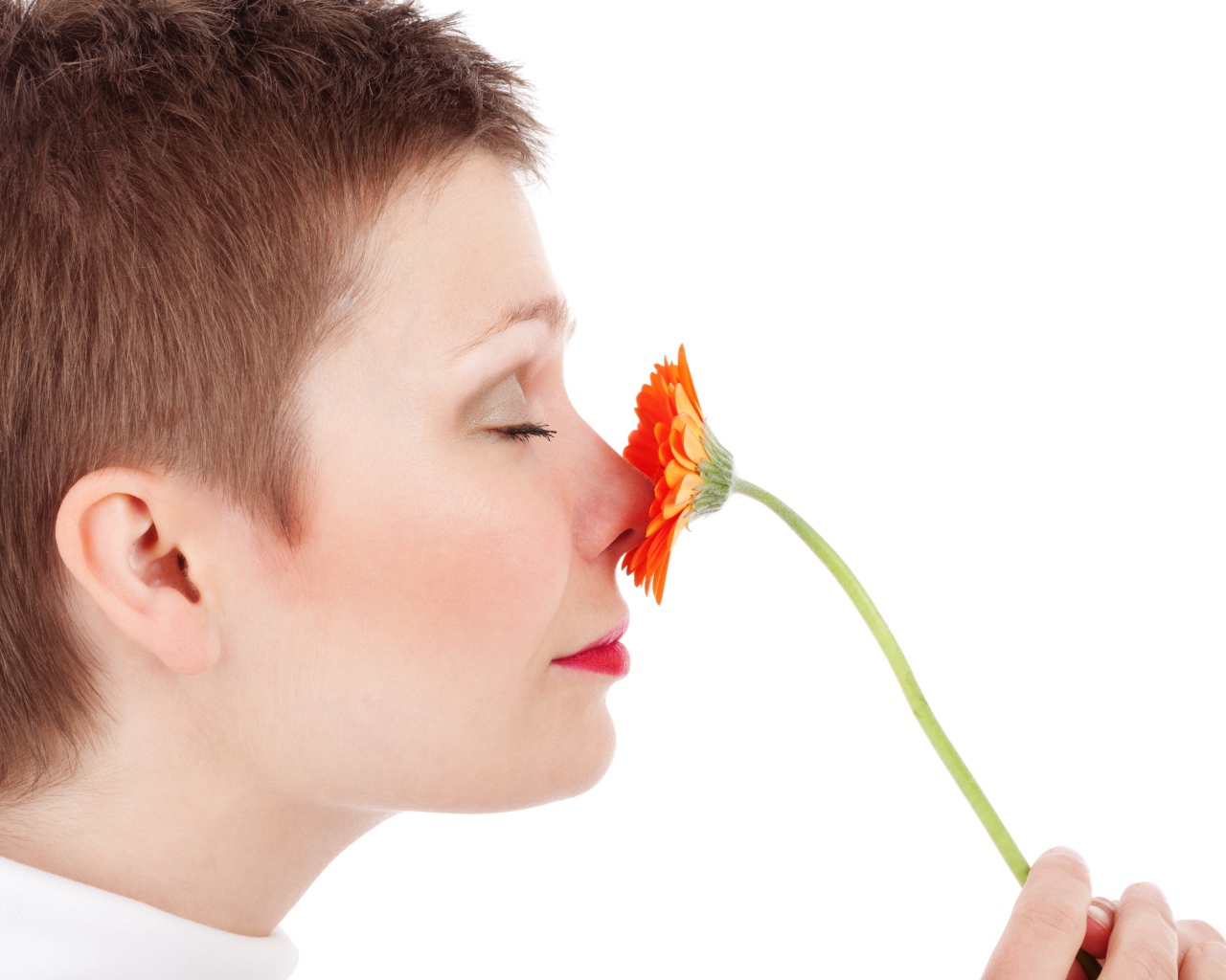 Женщина с закрытыми глазами с цветком герберы в руке