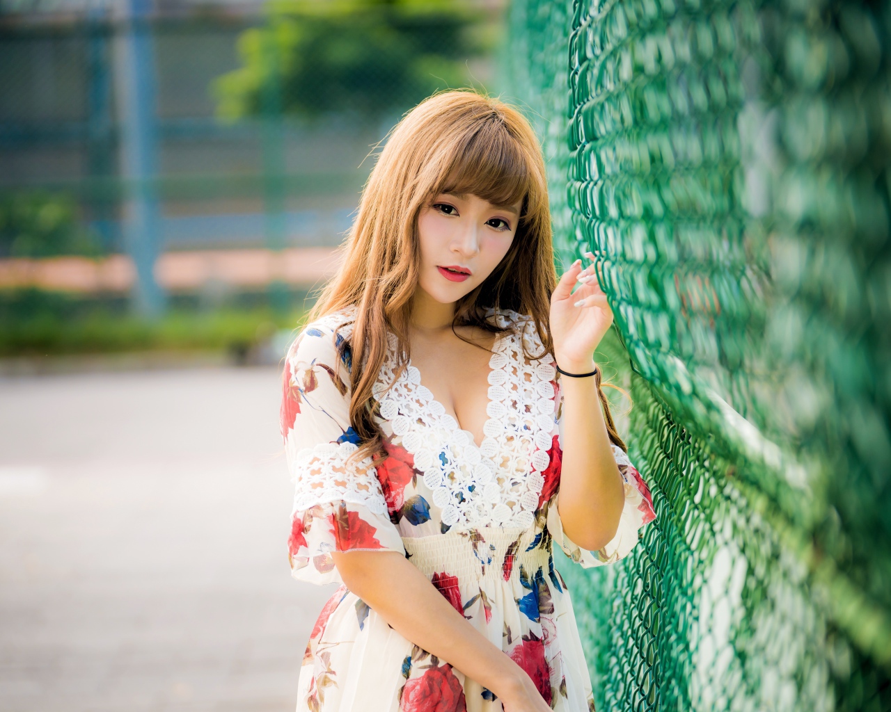 Молодая азиатка в платье у зеленой сетке 