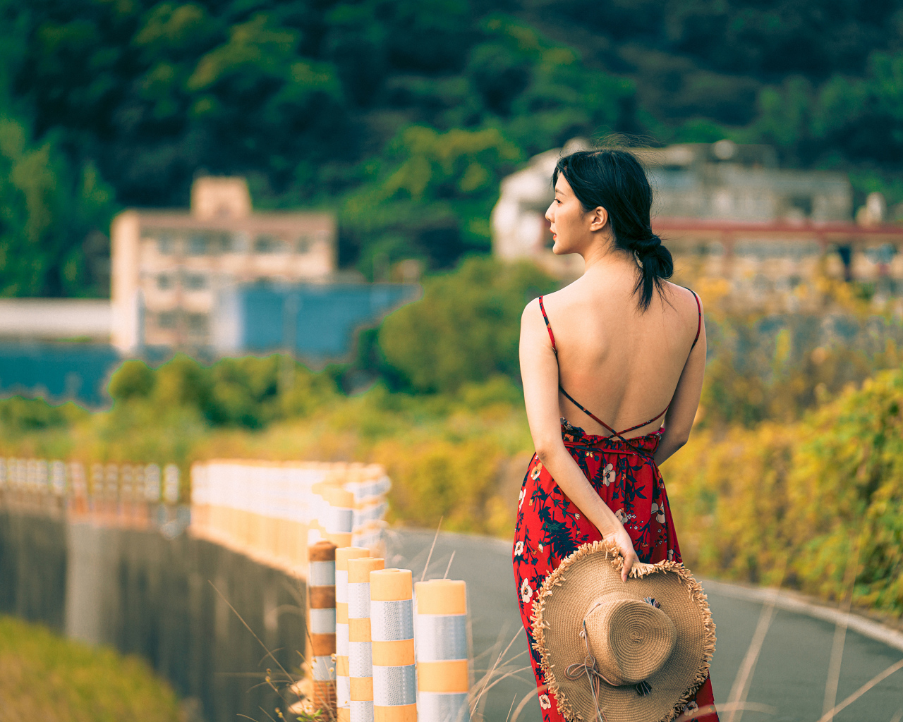 Молодая девушка азиатка в сарафане со шляпой в руке 