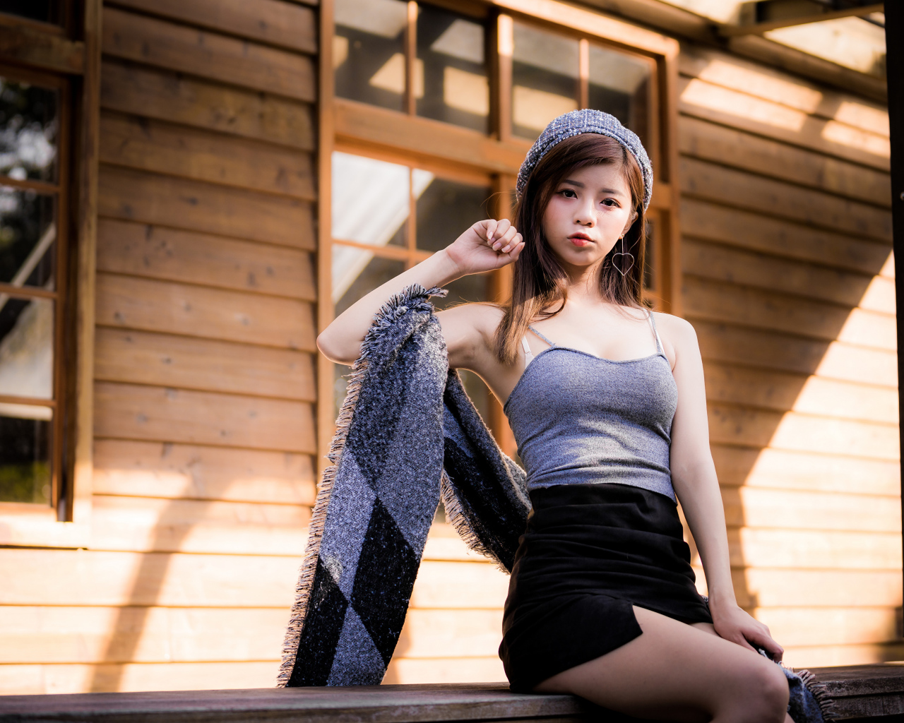 Молодая девушка азиатка в короткой юбке сидит на подоконнике 