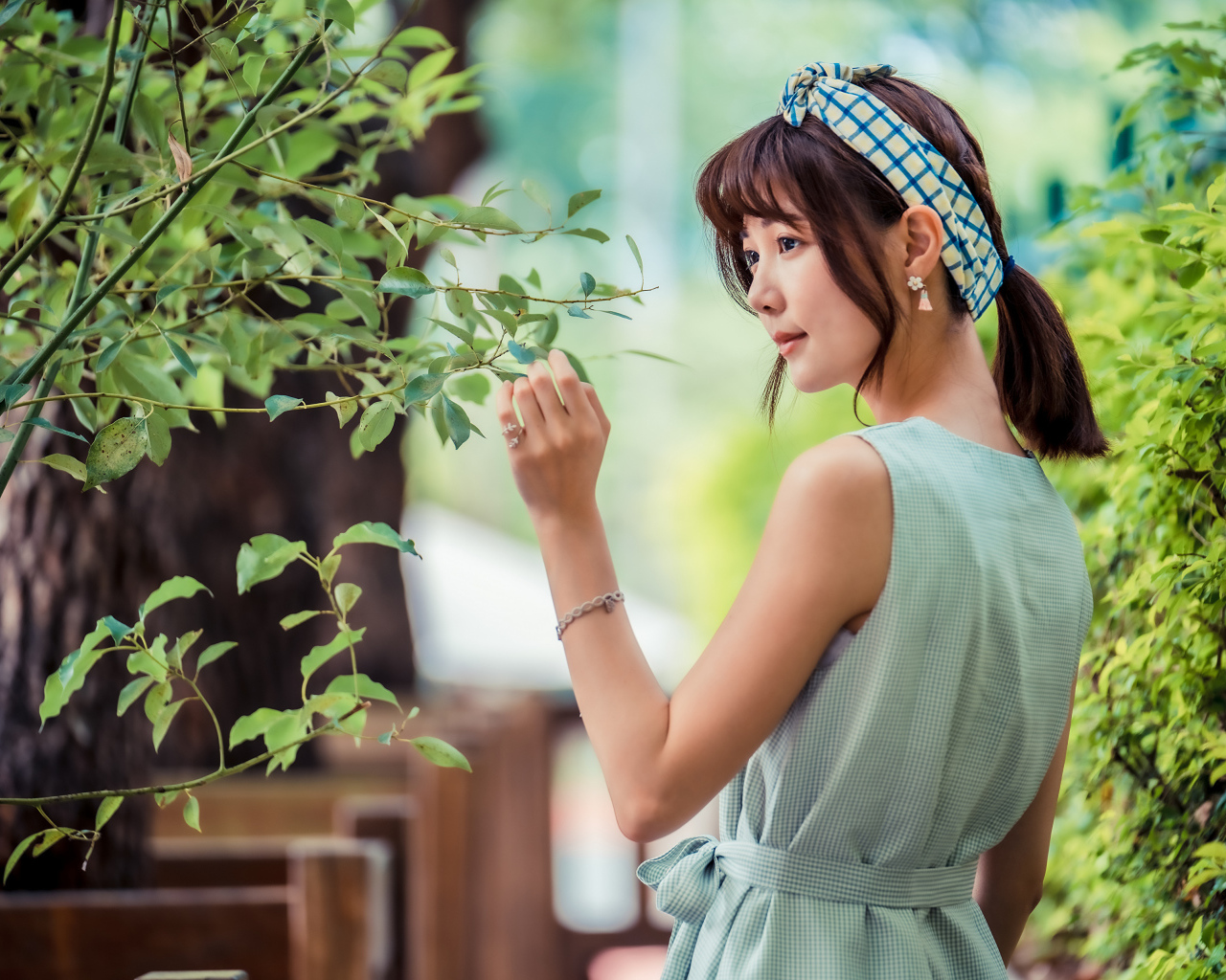 Молодая девушка азиатка с повязкой на голове у дерева 