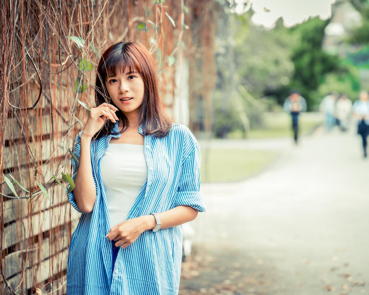 Молодая азиатка в рубашке у стены