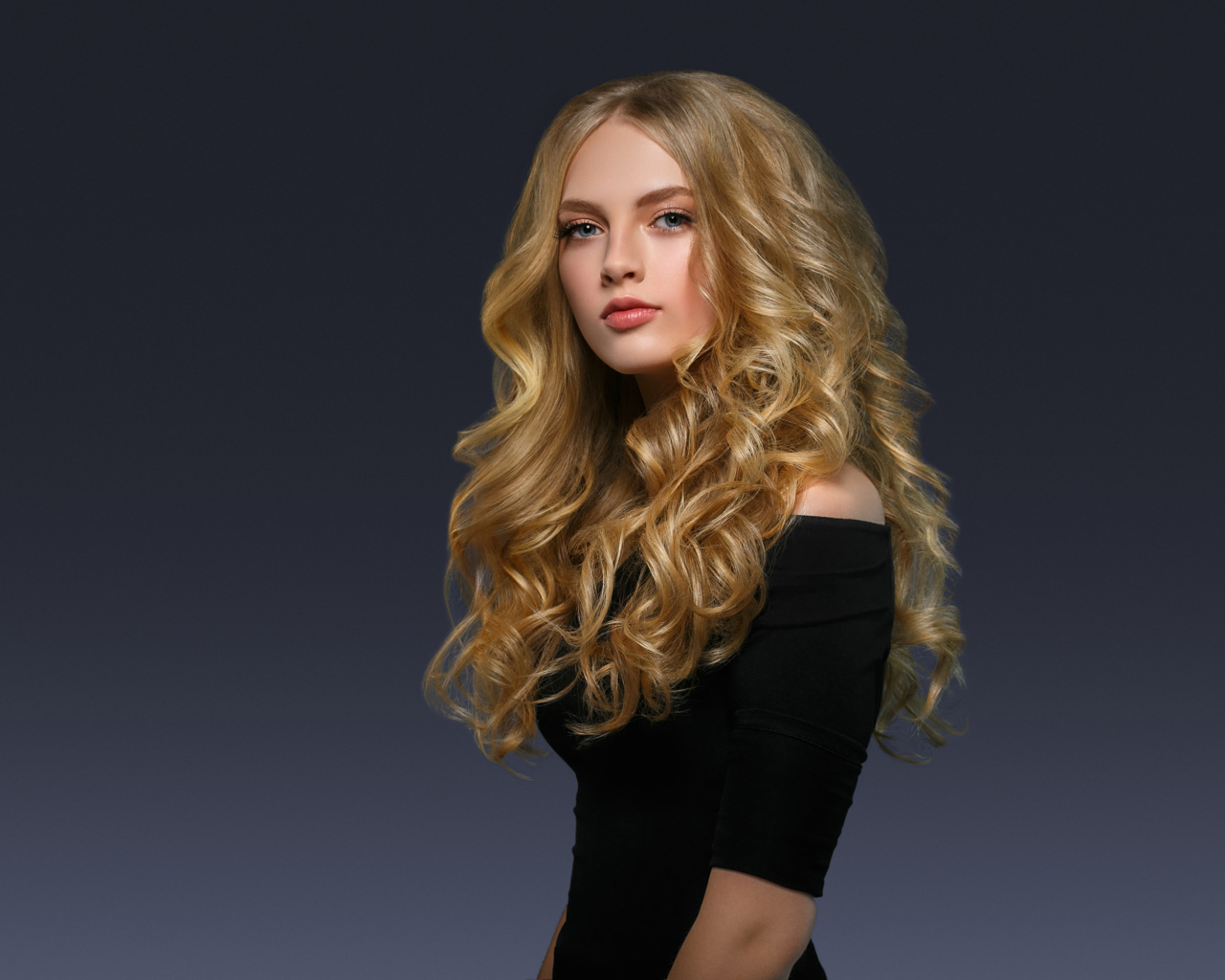 Молодая блондинка с красивыми длинными волосами в черном платье